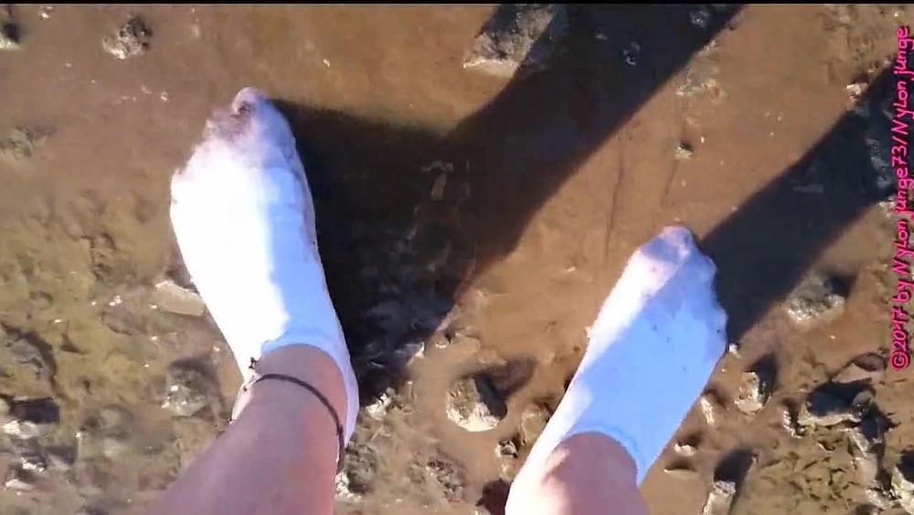 Weiße Sneaker Socken in der Pfütze